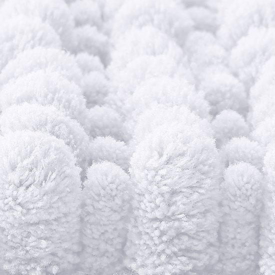 Gedetailleerd beeld van de textuur van een witte pluizige badmat.
