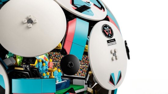 Binnenzijde LEGO voetbal met mini-stadion, tribunes, veld en miniatuurvoetballers. Turquoise, roze en witte buitenkant.