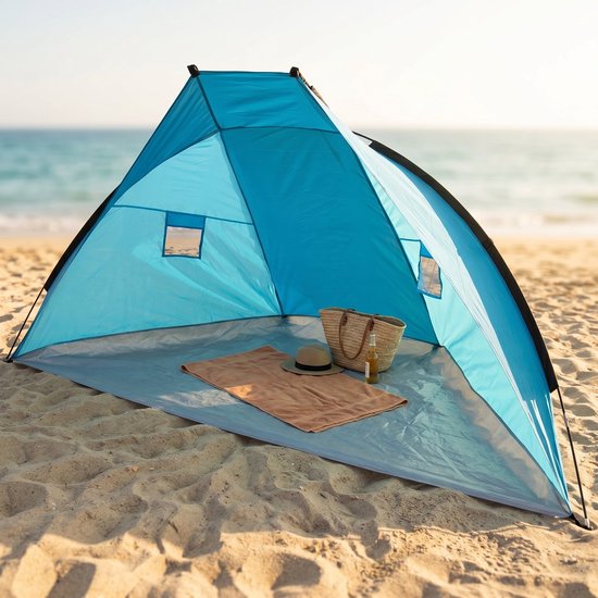 Blauwe strandtent op het strand met een handdoek, hoed en flesje op de grond. Biedt schaduw.