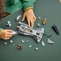 Kinderhanden bouwen een grijs LEGO Star Wars schip met bruine en gele minifiguren.