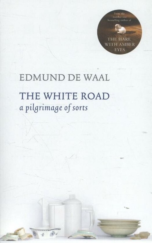 Boek 'The White Road' van Edmund de Waal. Bovenin staat 'From the number one bestselling author of THE HARE WITH AMBER EYES'. Onderin staan witte porseleinen kannen en kommen.
