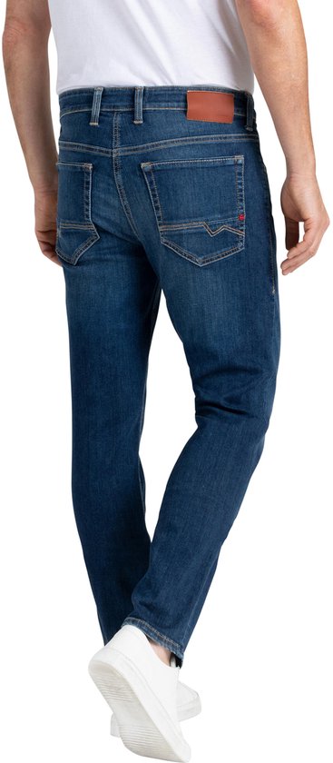 Achterkant van een man in een blauwe jeans met label en witte sneakers.