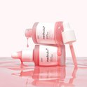Twee Medicube PDRN Pink Peptide Serum flesjes. Roze serum druipt uit de flesjes en spettert op een roze ondergrond.
