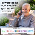 Een oudere man glimlacht terwijl hij een mobiele telefoon vasthoudt. Tekst: 4G-verbinding voor stabiele gesprekken.