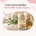 Meerdere brandende kaarsen in glazen potten en enkele kleine votiefkaarsen, op een houten ondergrond.