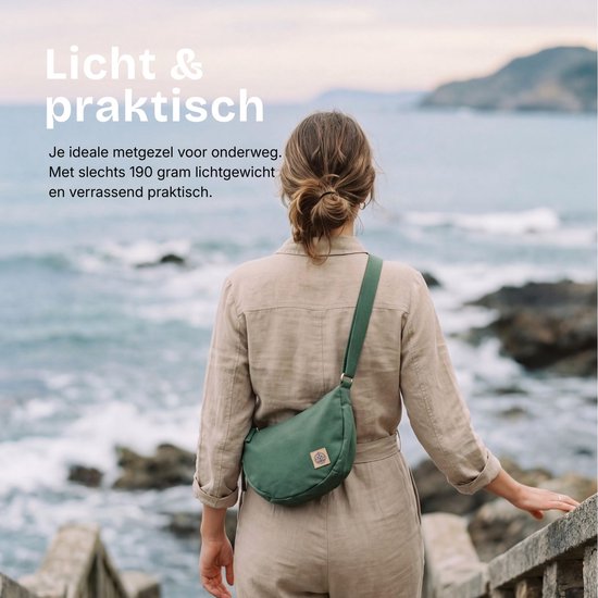 Vrouw met een groene half-moon tas, schoudertas op de rug, aan zee. Licht en praktisch.