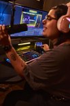 Een streamer met roze koptelefoon gebruikt een microfoon en bedient de Hercules Stream controller.