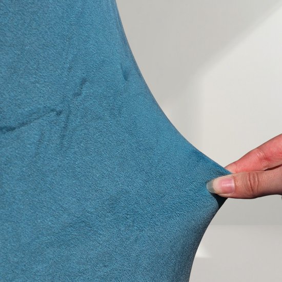 Hand die turquoise, elastische stof uitrekt.