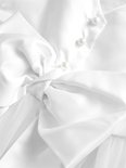 Close-up van een witte strik op een jurk met parelmoeren knoopjes en tule.