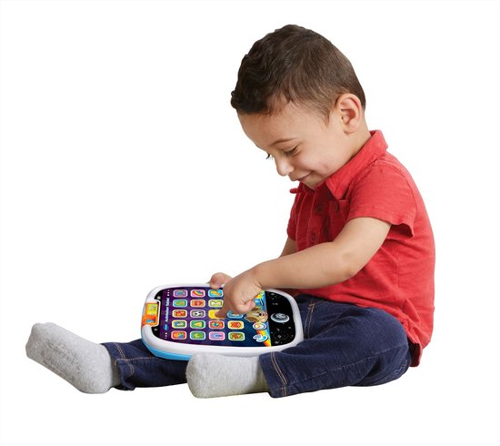 Jongen in rood shirt en spijkerbroek speelt met blauwe en witte VTech activiteiten tablet.