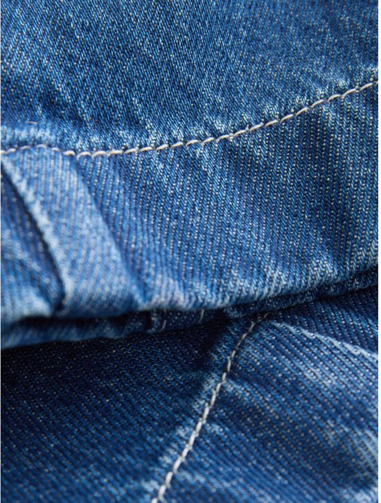 Detail van de stiksels en denim stof van een spijkerbroek.