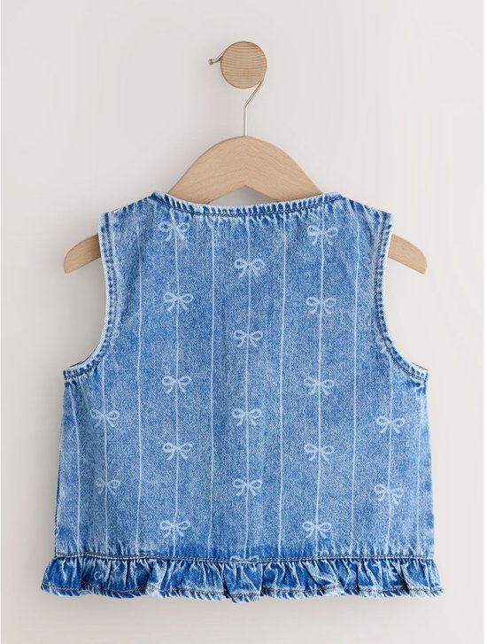 Achterkant van een blauw denim gilet met verticale strepen en strikprint, hangend aan een houten hanger.