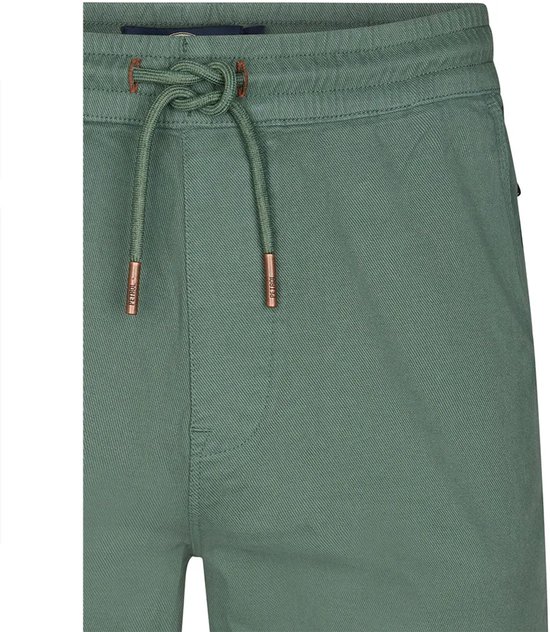 Close-up van de tailleband van een groene chino short met veter. Koperkleurige details op de veteruiteinden.