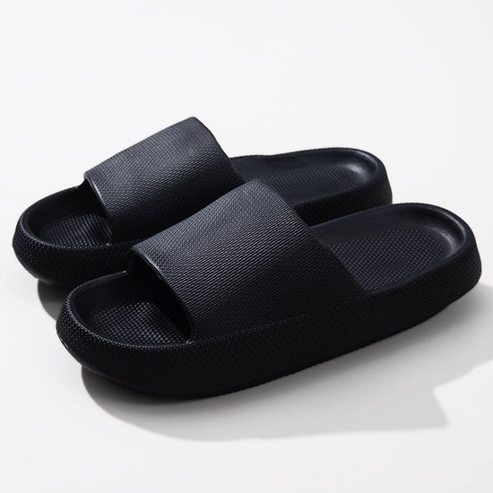 Paar zwarte slippers met dikke zolen en grove textuur.
