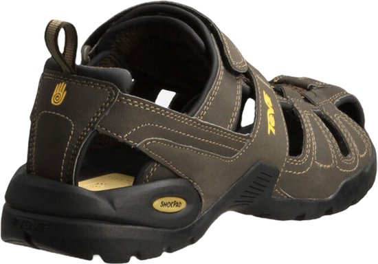 Achterkant van een donkerbruine Teva sandaal met open hiel, klittenbandsluiting en gele "Teva" logo.