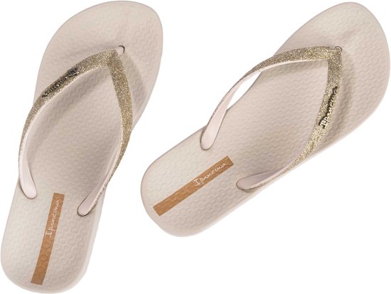 Beige Ipanema teenslippers met glitterbandjes op zwarte achtergrond.