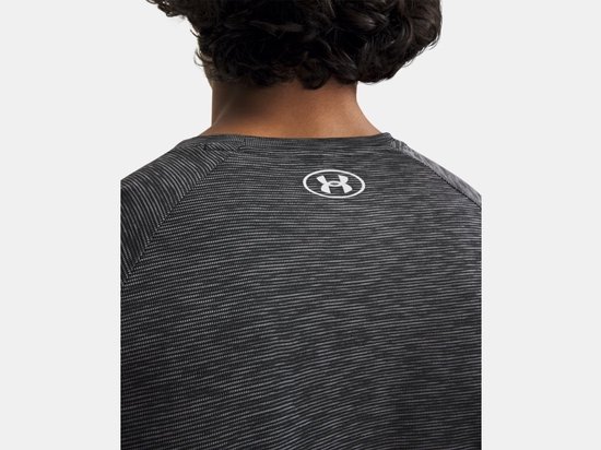 Detail van een zwart gestreept sportshirt met wit Under Armour logo op de achterkant van de nek.
