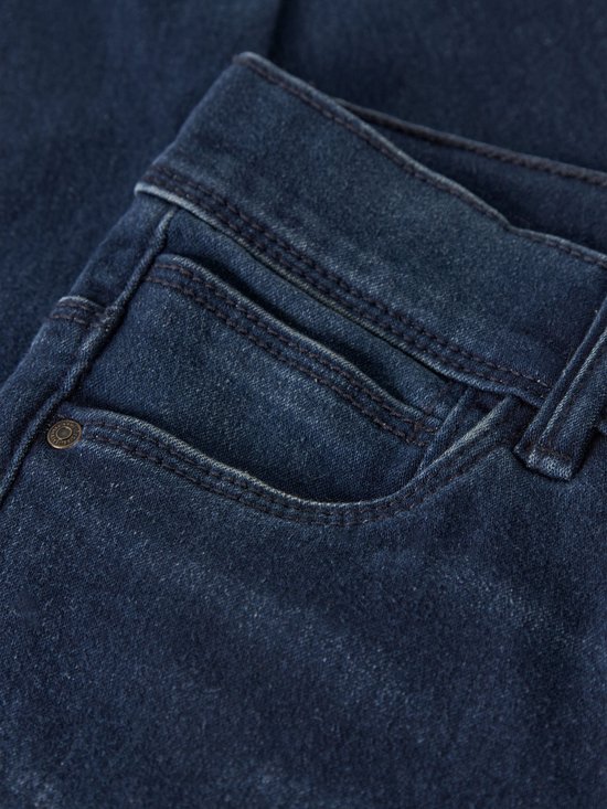 Detail van de zakken en het denim van een donkerblauwe skinny jeans.