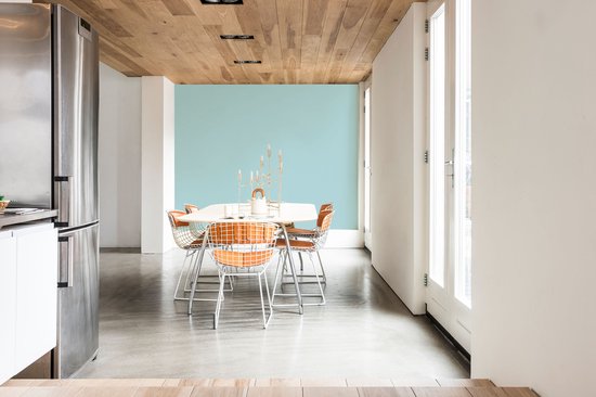 Eetkamer met lichtblauwe muur, houten plafond en oranje stoelen.