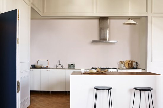 Moderne keuken met witte kasten, een fornuis met RVS afzuigkap en een eiland met barkrukken.