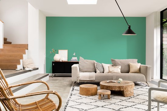 Woonkamer met een bank, bijzettafels en een groen geverfde muur.