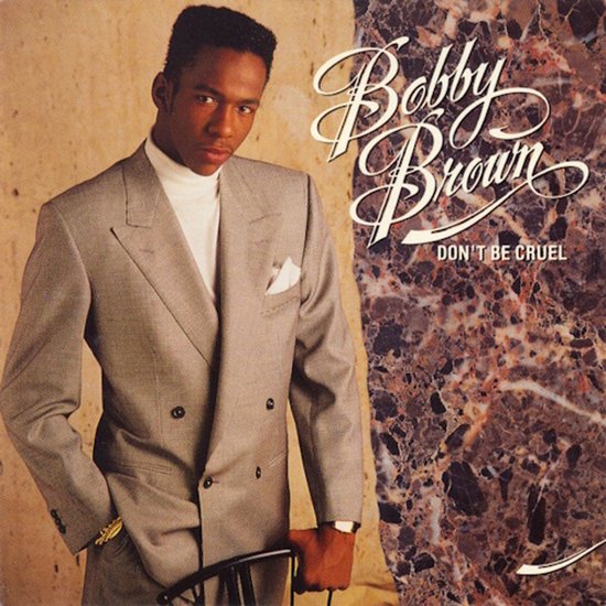 Bobby Brown draagt een grijsDouble-breasted pak met een witte coltrui. De titel van het album, "Bobby Brown DON'T BE CRUEL", staat op de afbeelding.