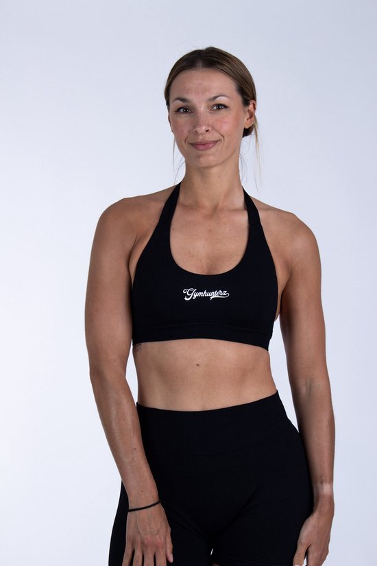 Vrouw in zwarte sportbeha met "Gymhunterz" logo, witte achtergrond.