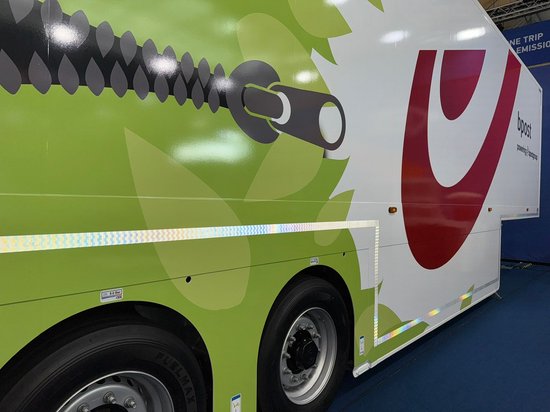 Zijkant van een vrachtwagen met een groen bladmotief en een rits. Op de achterkant staat 'bpost'.