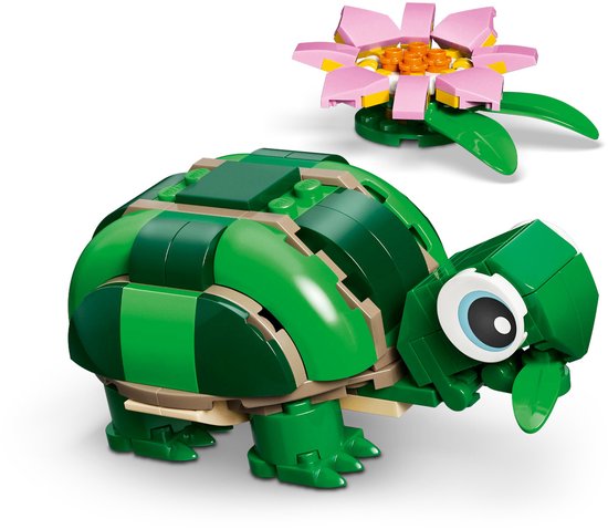 Een groene legoschildpad met een bolle schaal, grote ogen en een roze bloem met groene blaadjes ernaast.