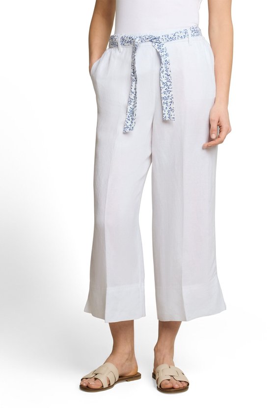 Model draagt een witte wijde driekwartbroek met een riem met blauwe bloemenprint.