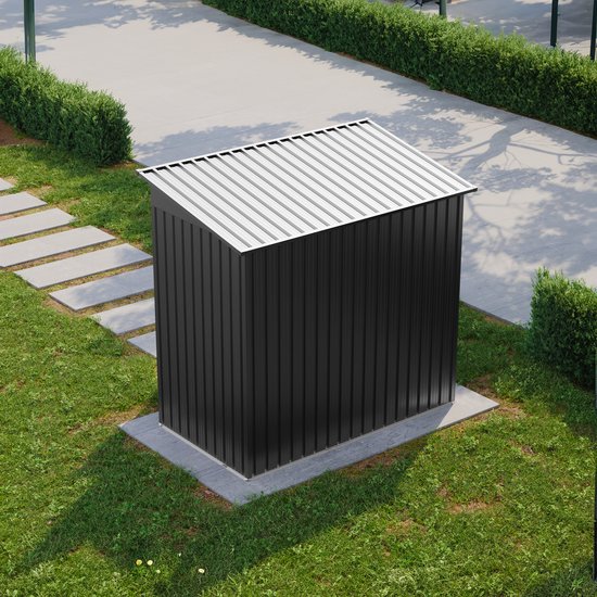 Gesloten zwarte metalen tuinschuur in een tuin, met stenen pad.