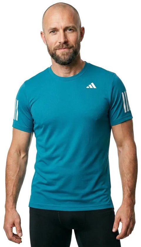 Man met baard draagt een blauw Adidas sportshirt met korte mouwen en witte Adidas strepen op de mouwen en borst.