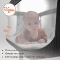 Baby in een donkergrijze co-sleeper met grote mesh-panelen voor ventilatie.