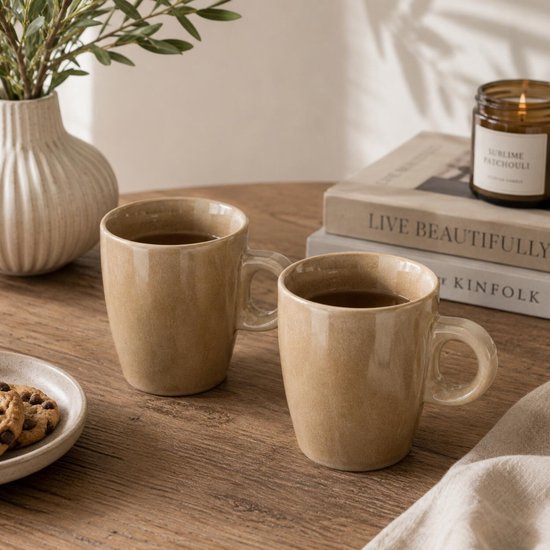 Twee beige mokken met handvat, gevuld met koffie, op een houten tafel.