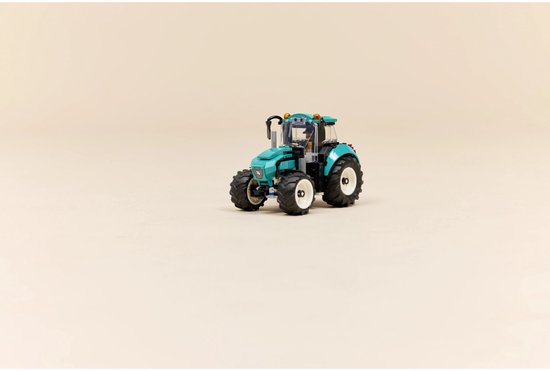 Felgroene tractor met grote banden en witte velgen, op een lichte achtergrond.