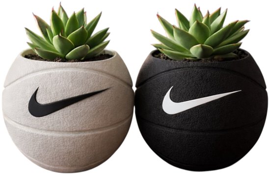 Twee basketbalvormige plantenpotten, één crèmekleurig en één zwart, beide met zwart Nike-logo, met succulente planten.