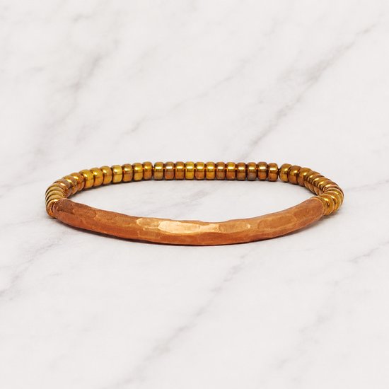 Bracelet en cuivre avec perles dorées et un tube central courbé et martelé.