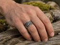 Hand met een zilverkleurige ring met Viking Raven patroon.