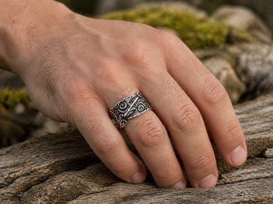 Hand met een zilverkleurige ring met Viking Raven patroon.