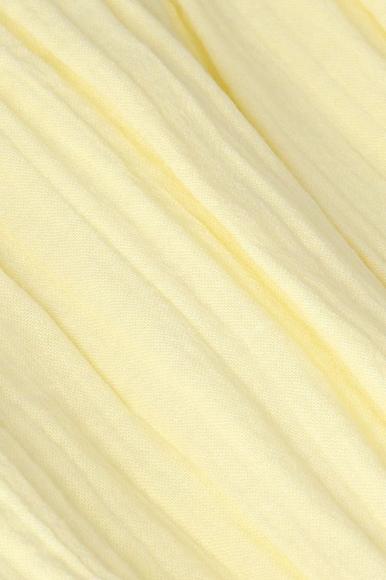 Detail van lichtgele stof met verticale plooien.