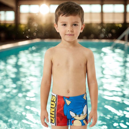 Jongetje aan het zwembad draagt een zwembroek met Sonic de egel. De zwembroek is rood met blauw en heeft Sonic's gezicht erop.
