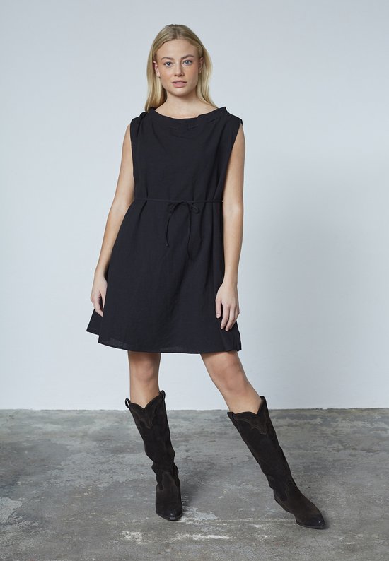 Mannequin de face dans une robe noire avec ceinture à nouer, encolure bateau et détails de nœuds sur les épaules.