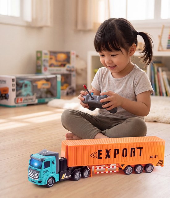 Blauwe en oranje speelgoed vrachtwagen met "EXPORT" op de trailer. Een kind speelt ermee op de grond.