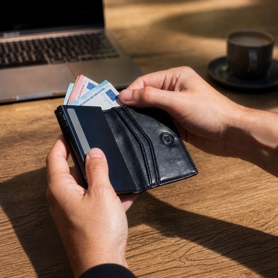 Zwarte lederen portemonnee met een gleuf voor briefgeld en meerdere vakjes voor pasjes. Een persoon haalt er geld uit.