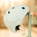 Lichtgroene kinderhelm met krokodillenprint, bevestigd aan een deel van een step.