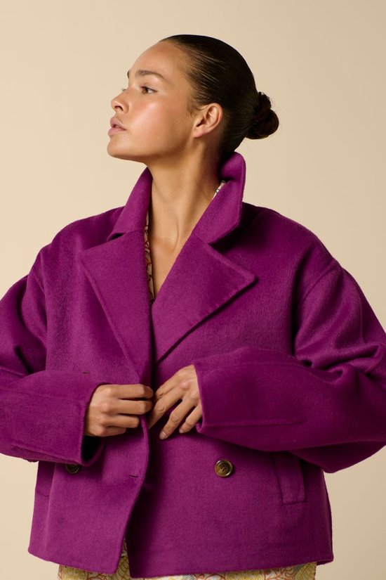 Femme portant un manteau de laine violet, gros plan sur le col et les boutons.