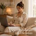 Een vrouw met een Sensibaby borstkolf op de borst, werkend op een laptop.