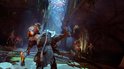 Kratos vecht met een monster met vlammen, met kleine demonen op de achtergrond.