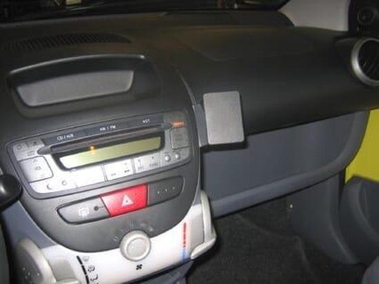Een grijze Brodit houder voor auto's, gemonteerd op een zwart dashboard naast een radio, met een ventilatierooster rechts.