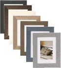 Stapel van fotolijstjes in verschillende kleuren (grijs, blauw, bruin, beige, wit, donkerbruin, zwart) met ruw oppervlak.